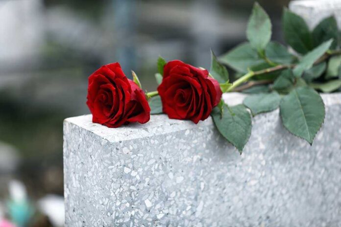 Red,Roses,On,Light,Grey,Tombstone,Outdoors.,Funeral,Ceremony