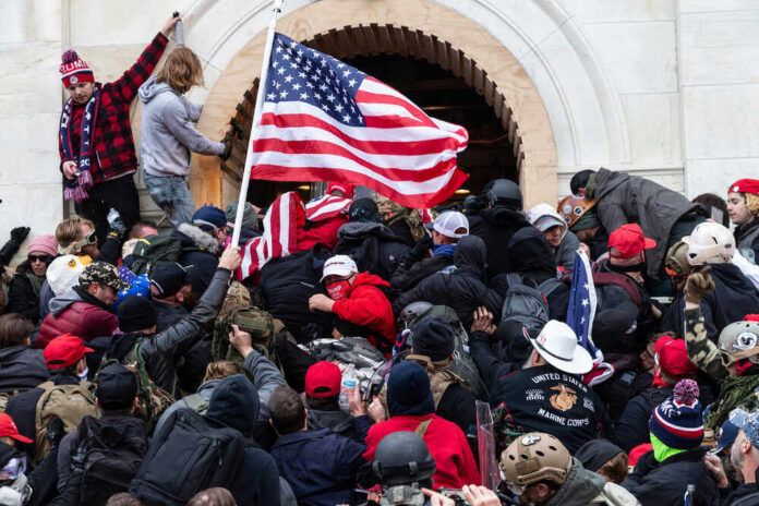 Crowd with American flags storming a building entrance.