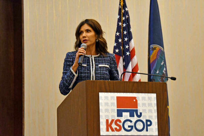 shutterstock_1962398782.jpg featured image Kristi Noem speaking at KS GOP event podium.