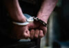 Close-up of hands in handcuffs behind back.