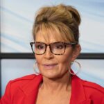 Sarah Palin glasses, red jacket, and background window.