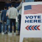 People in line next to Vote Here sign