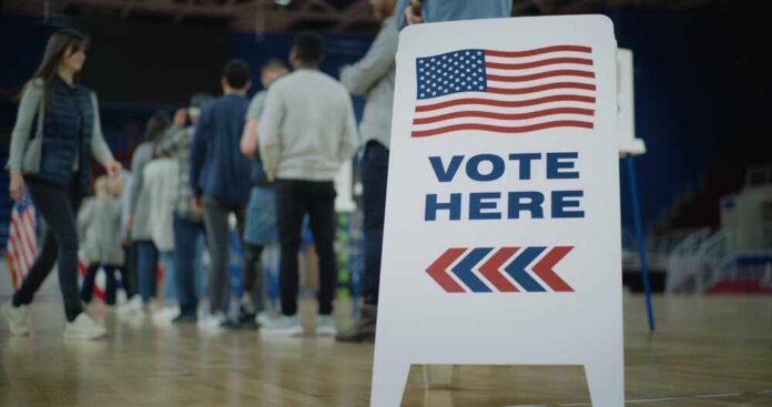 shutterstock_2454758105.jpg featured image People in line next to Vote Here sign