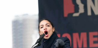 Alexandria Ocasio-Cortez passionately speaking at a podium outside.