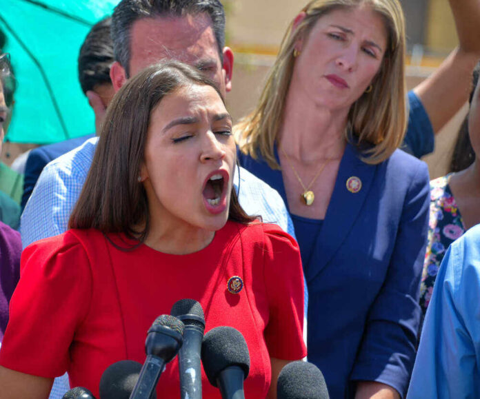 shutterstock_1439783054.jpg featured image Alexandria Ocasio-Cortez speaking passionately at microphones.