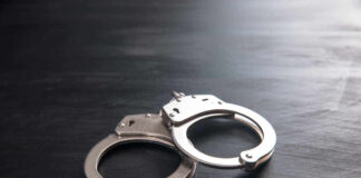 Metal handcuffs on a dark textured surface.