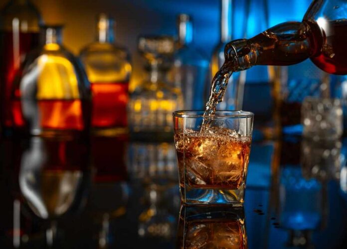 shutterstock_2459806379.jpg featured image Pouring whiskey into a glass with ice