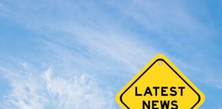 Yellow sign with latest news text against sky