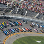 Race cars on Daytona track with large audience watching