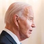 Joe Biden in a suit speaking, facing right.