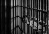 Rusty prison cell bars in dim lighting.