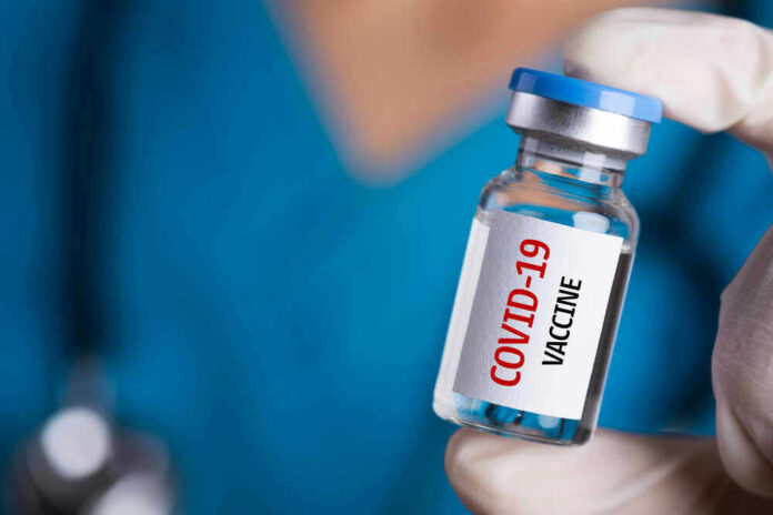 Person holding a vial labeled COVID19 Vaccine