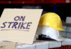 Sign reads On Strike near yellow hardhat