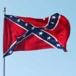 Confederate flag waving against a clear blue sky