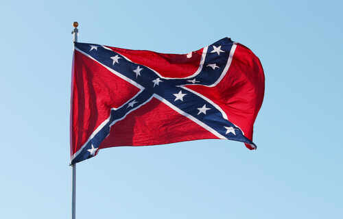 Confederate flag waving against a clear blue sky