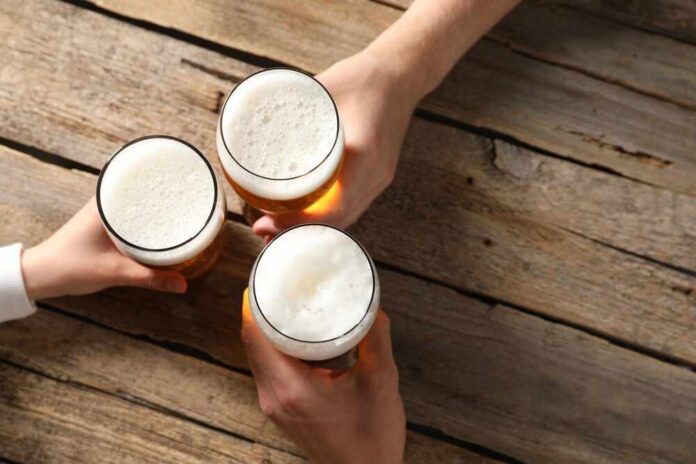 Three hands holding beer glasses in a toast