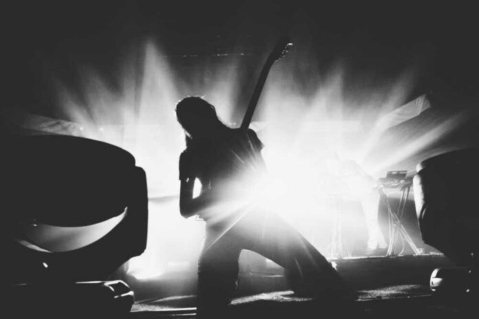 shutterstock_1069716398.jpg Silhouetted guitarist performing on stage with dramatic lighting