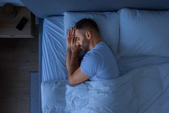 shutterstock_2396166233.jpg A man sleeping peacefully in a bed