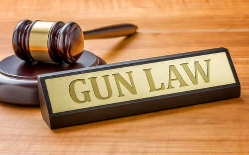 shutterstock_431719678.jpg A gavel and a nameplate reading 'GUN LAW' on a wooden surface