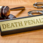 MURDERER Faces DEATH PENALTY Gavel handcuffs and death penalty sign on table