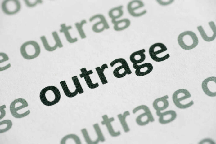 Close-up of the word 'outrage' printed in bold on paper
