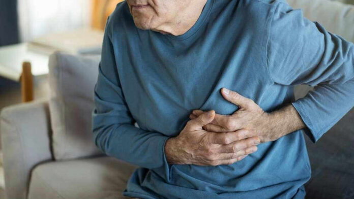 Man clutching chest in pain, sitting on couch.