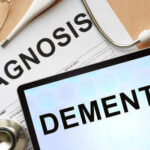 Medical diagnosis paperwork and a tablet displaying the word Dementia