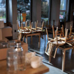 An empty cafe with stacked wooden chairs and boxes on a table
