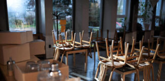 An empty cafe with stacked wooden chairs and boxes on a table