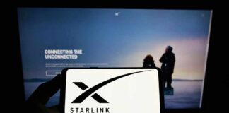 A hand holding a smartphone displaying the Starlink logo in front of a screen showing a connectivity message