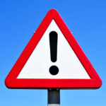 Trusted Educator Was ILLEGAL Alien — Wild DETAILS A triangular warning sign with an exclamation mark against a blue sky