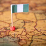 Trump’s UNEXPECTED Nigeria Move A small Nigerian flag placed on a map of Africa, highlighting Nigeria