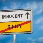 A road sign displaying 'INNOCENT' with an arrow pointing up and 'GUILTY' crossed out