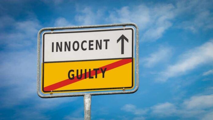 A road sign displaying 'INNOCENT' with an arrow pointing up and 'GUILTY' crossed out