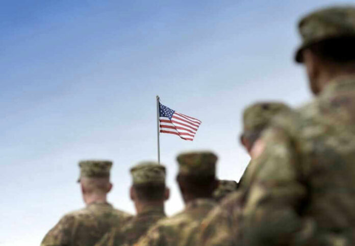 Soldiers in uniform with American flag in background.