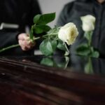 TV Star’s Death Announced — Fans Saddened Two individuals placing white roses on a coffin during a funeral