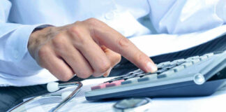 Doctor using calculator with stethoscope on the table.