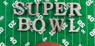 A football and the words 'SUPER BOWL' on a green football field background