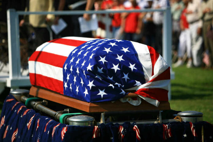 shutterstock_106701479.jpg American flag draped over a casket at ceremony.