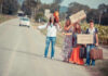 Group of young people hitchhiking on a rural road with signs
