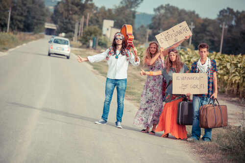 Group of young people hitchhiking on a rural road with signs