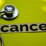 A stethoscope next to the word 'cancer' on a yellow background