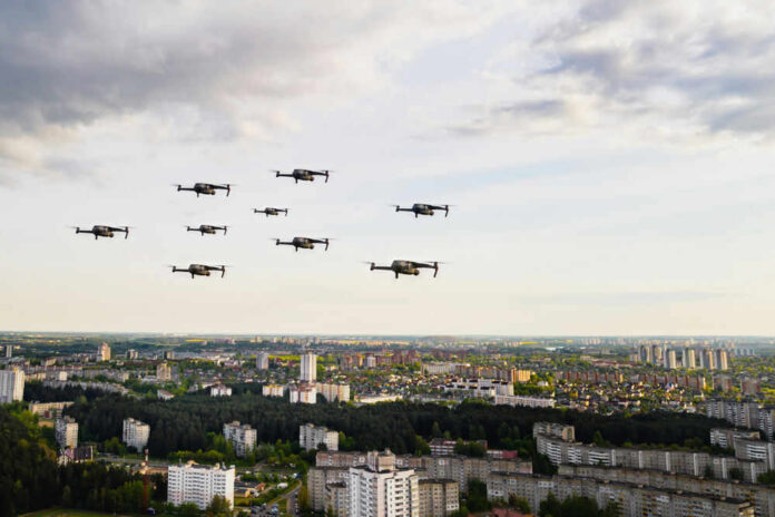 Drones flying over a cityscape under cloudy sky.