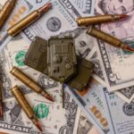 A toy military vehicle surrounded by bullets and U.S. dollar bills
