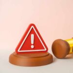 A red warning sign next to a legal gavel on a light background