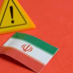 Iranian flag next to a caution sign on a red background