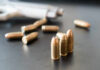 Close-up of bullets on a dark surface with a handgun in the background