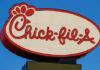 Chick-fil-A restaurant sign illuminated against a blue sky