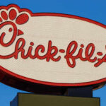 Chick-fil-A restaurant sign illuminated against a blue sky