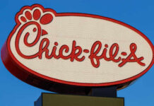 Chick-fil-A restaurant sign illuminated against a blue sky